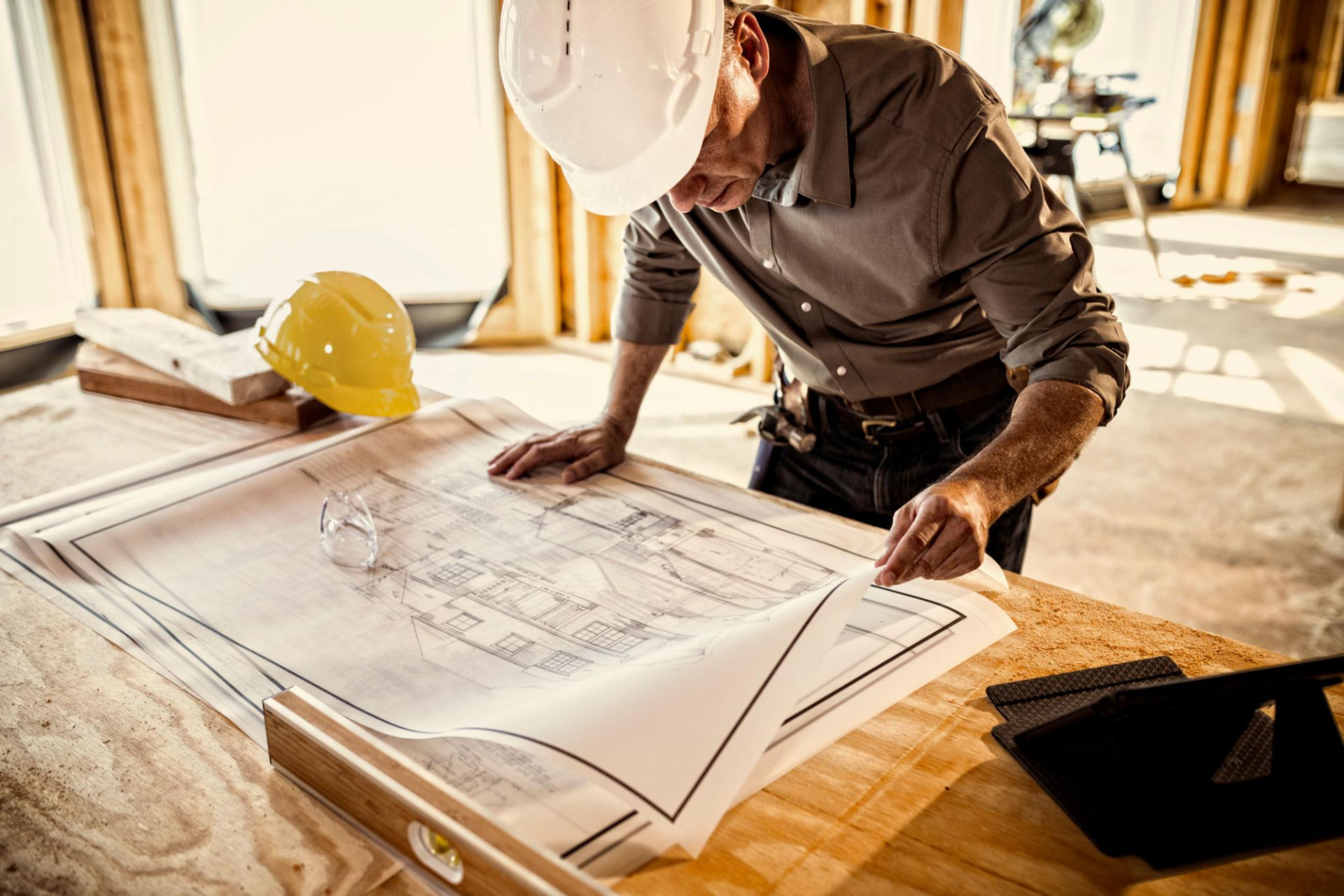 Builder reviewing house plans on site